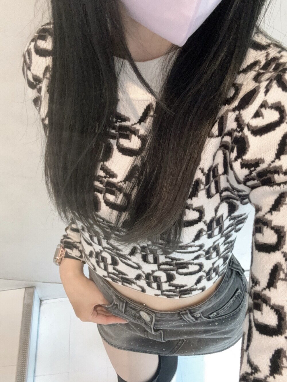 ホワイト系のニット/セーター、ブラック系のデニムスカート、ブラック系のダウンジャケット/コートを着用したレディースの秋コーディネートの7枚目の写真