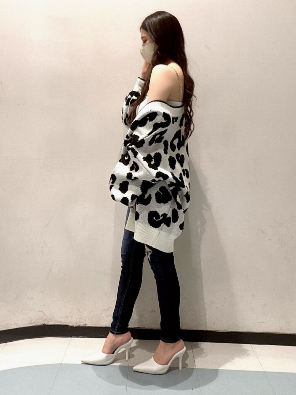 ホワイト系のカーディガン/ボレロ、ホワイト系のキャミソール、ブルー系のデニムパンツを着用したレディースの春コーディネートの2枚目の写真