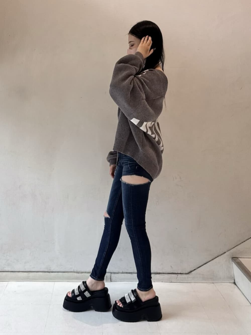 ホワイト系のチューブトップ、グレー系のカーディガン/ボレロ、ブルー系のデニムパンツを着用したレディースの春コーディネートの2枚目の写真