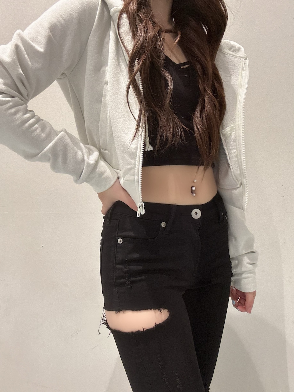 ホワイト系のパーカー、ブラック系のキャミソール、ブラック系のデニムパンツを着用したレディースの春コーディネートの4枚目の写真