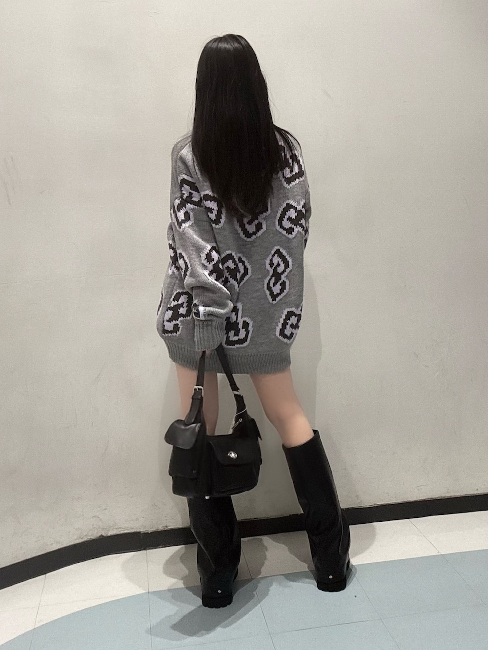 グレー系のニット/セーター、ブラック系のスカート、ブラック系のブーツを着用したレディースの秋コーディネートの4枚目の写真
