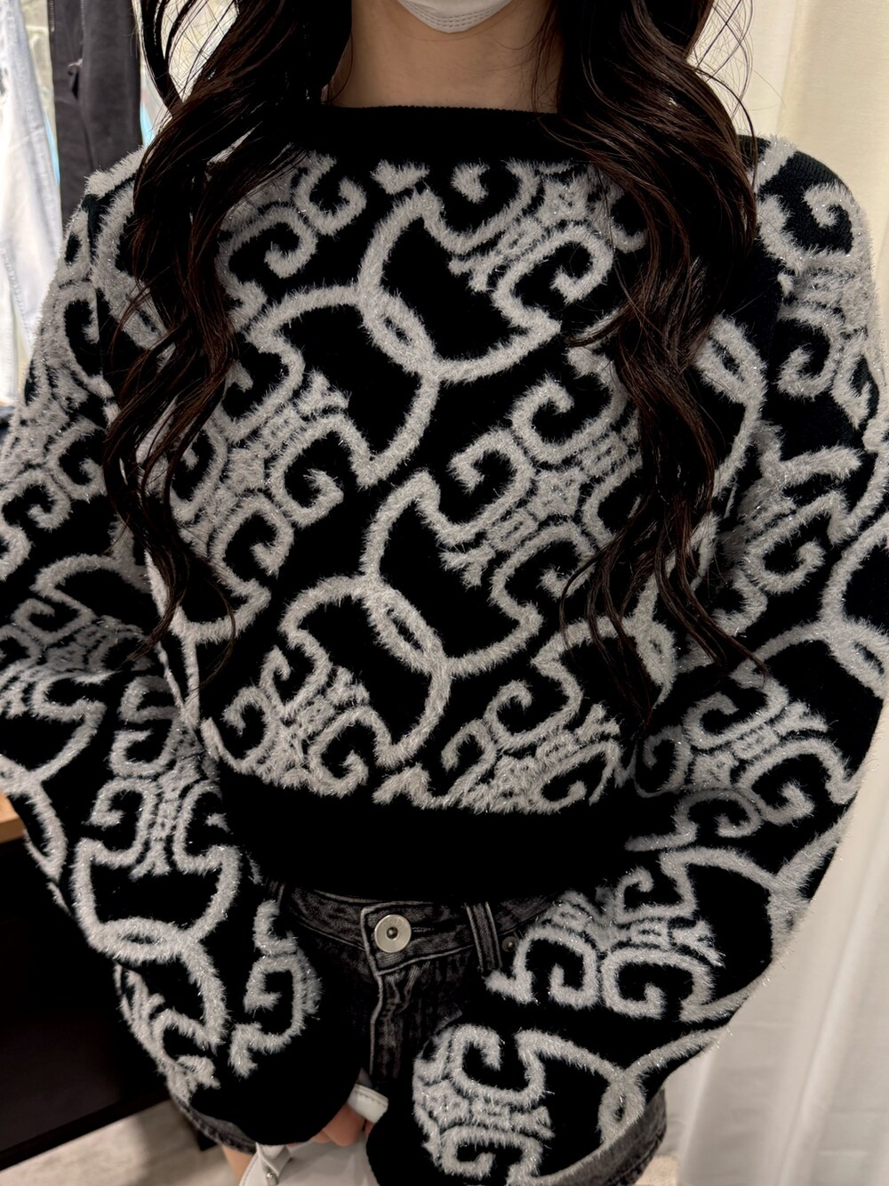 ブラック系のニット/セーター、ブラック系のデニムスカート、ホワイト系のハンドバッグを着用したレディースの冬コーディネートの4枚目の写真