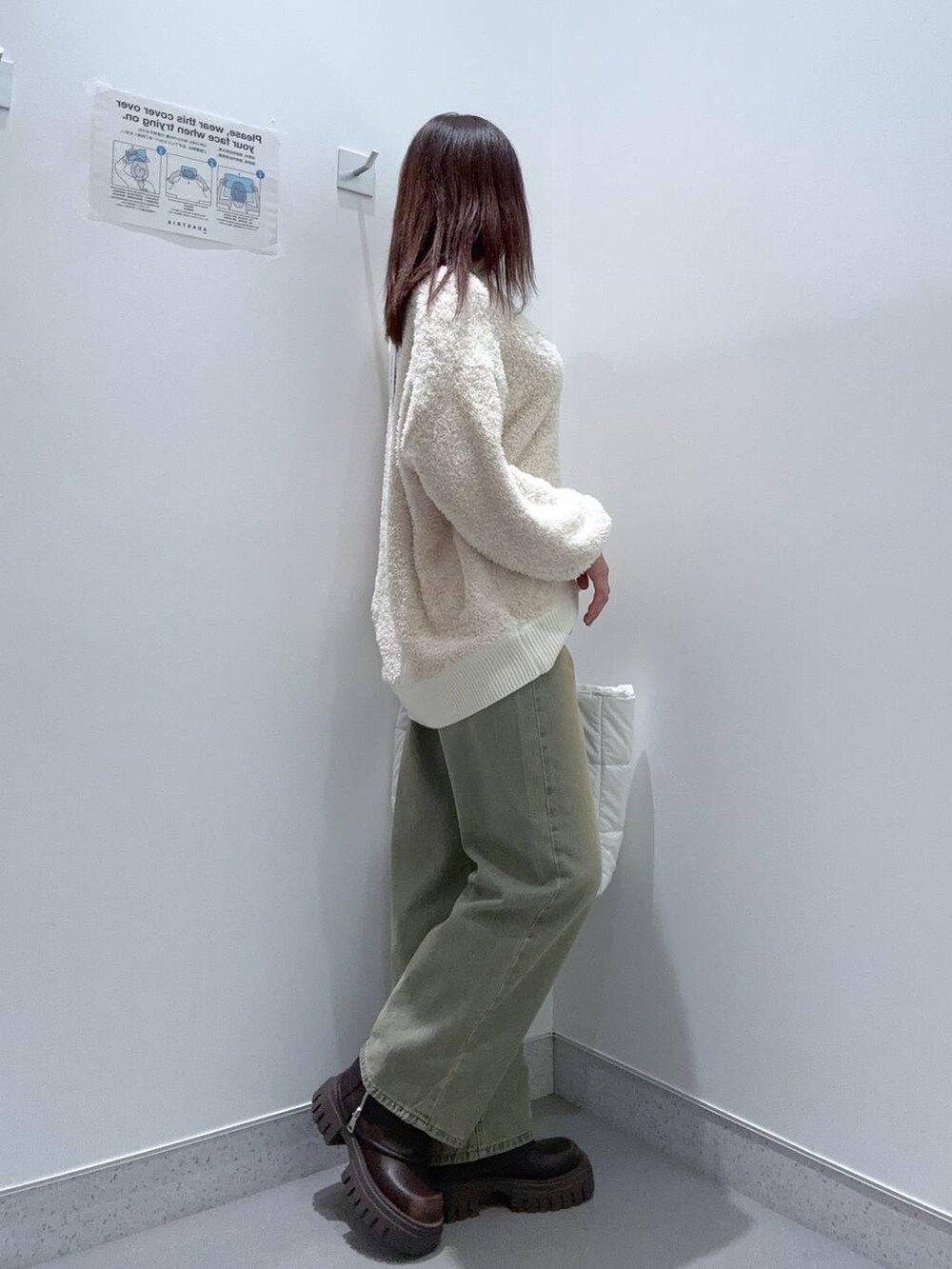 ホワイト系のハンドバッグ、ブルー系のデニムパンツ、ブラウン系のブーツを着用したレディースの冬コーディネートの2枚目の写真