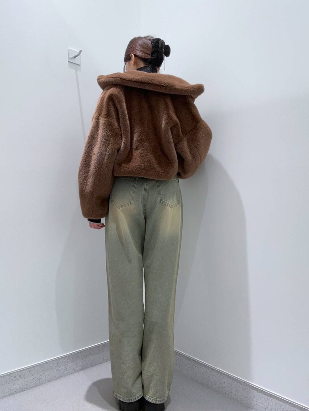 ブラウン系のブルゾン、ブルー系のデニムパンツ、ブラック系のブーツを着用したレディースの秋コーディネートの3枚目の写真