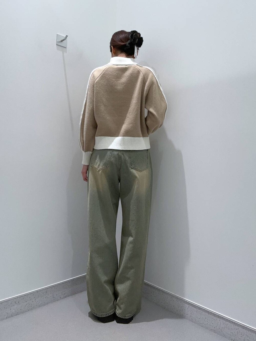 ブルー系のデニムパンツ、ブラック系のブーツ、ベージュ系のニット/セーターを着用したレディースの秋コーディネートの3枚目の写真