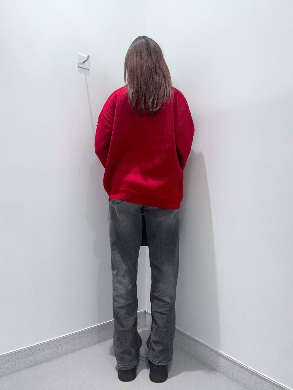 ブラック系のデニムパンツ、ブラウン系のショルダーバッグ、レッド系のニット/セーターを着用したレディースの秋コーディネートの2枚目の写真