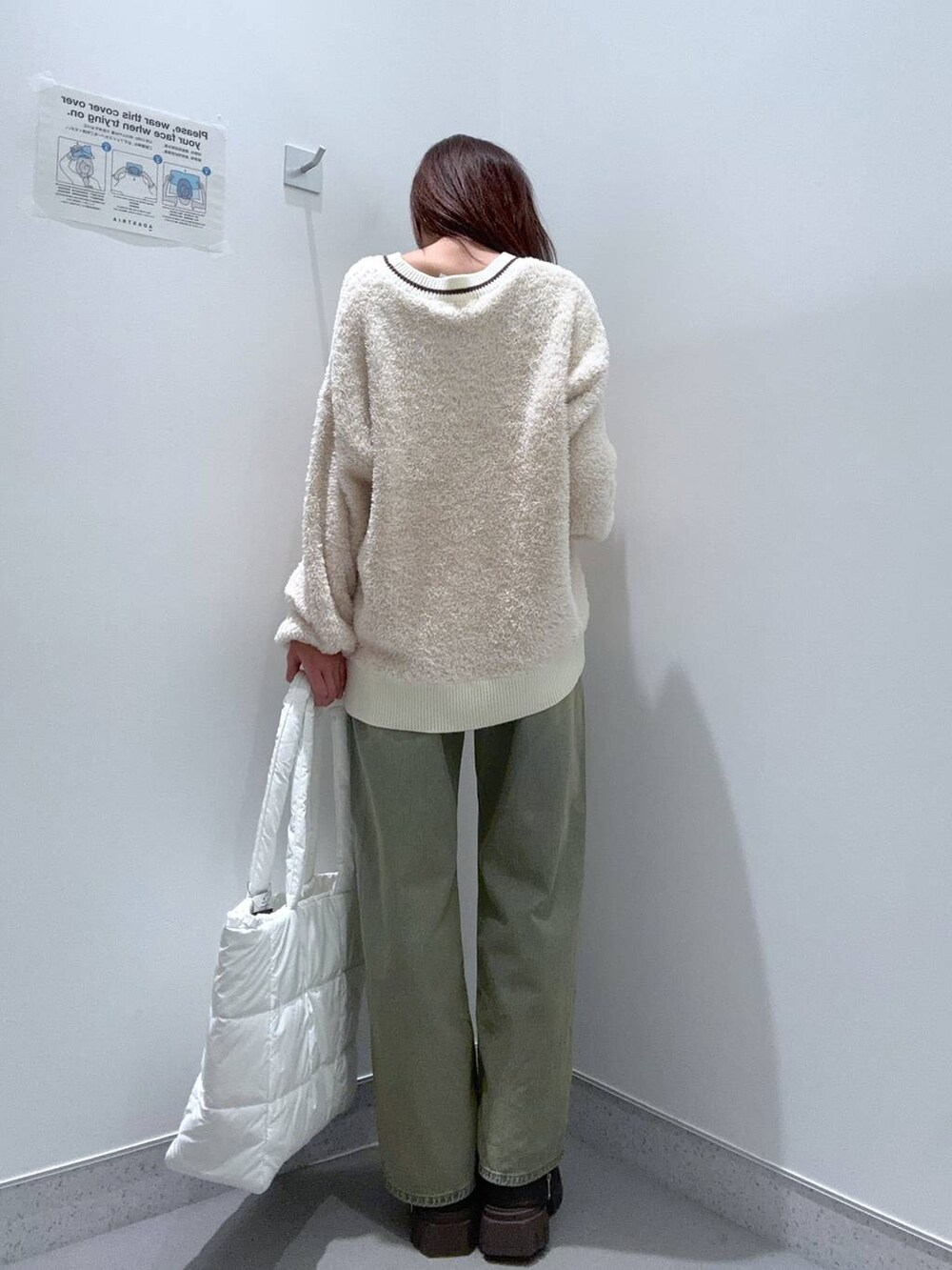 ホワイト系のハンドバッグ、ブルー系のデニムパンツ、ブラウン系のブーツを着用したレディースの冬コーディネートの3枚目の写真