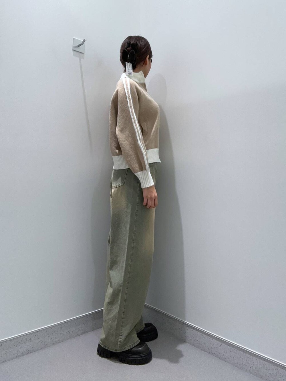 ブルー系のデニムパンツ、ブラック系のブーツ、ベージュ系のニット/セーターを着用したレディースの秋コーディネートの2枚目の写真