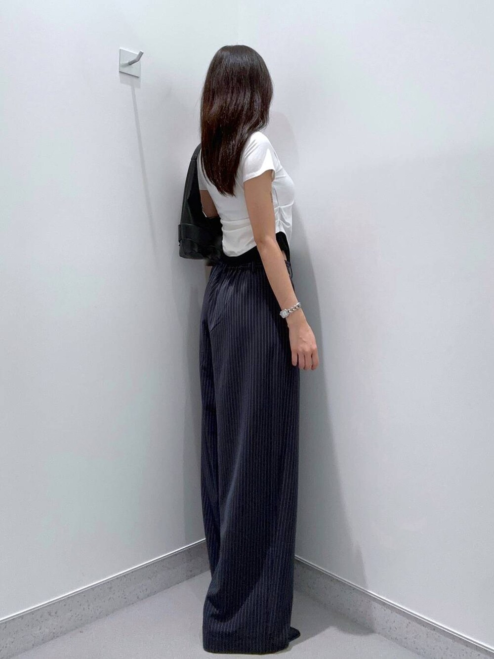 ブラック系のパンプス、ブラック系のショルダーバッグ、ブラック系のTシャツ/カットソーを着用したレディースの夏コーディネートの2枚目の写真