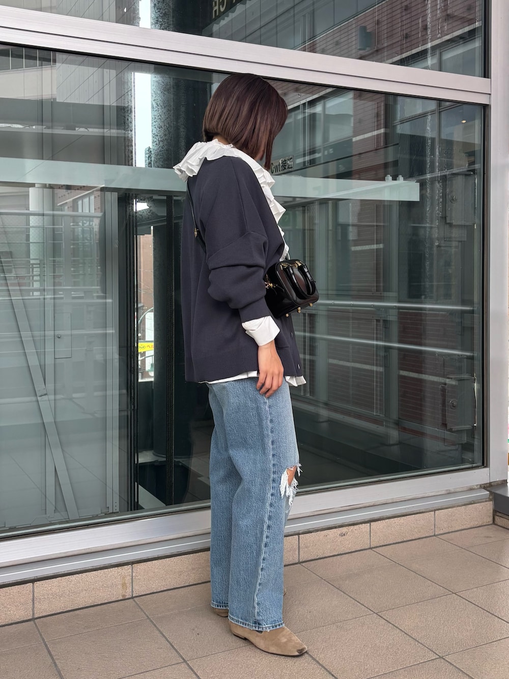 ブルー系のデニムパンツ、ベージュ系のローファー、グレー系のカーディガン/ボレロを着用したレディースの秋コーディネートの2枚目の写真