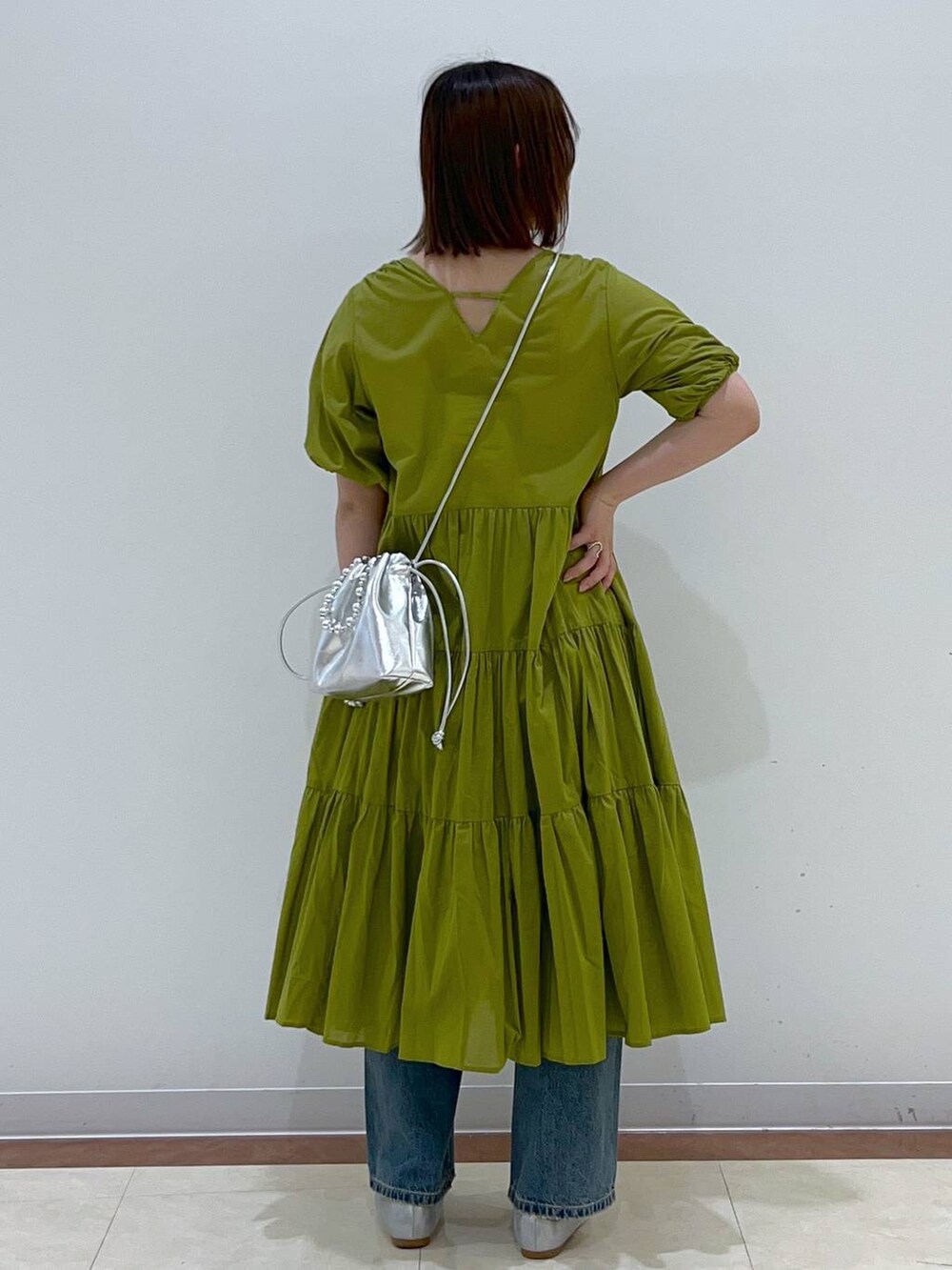 シルバー系のショルダーバッグ、イエロー系のワンピース、ブルー系のデニムパンツを着用したレディースの春コーディネートの3枚目の写真