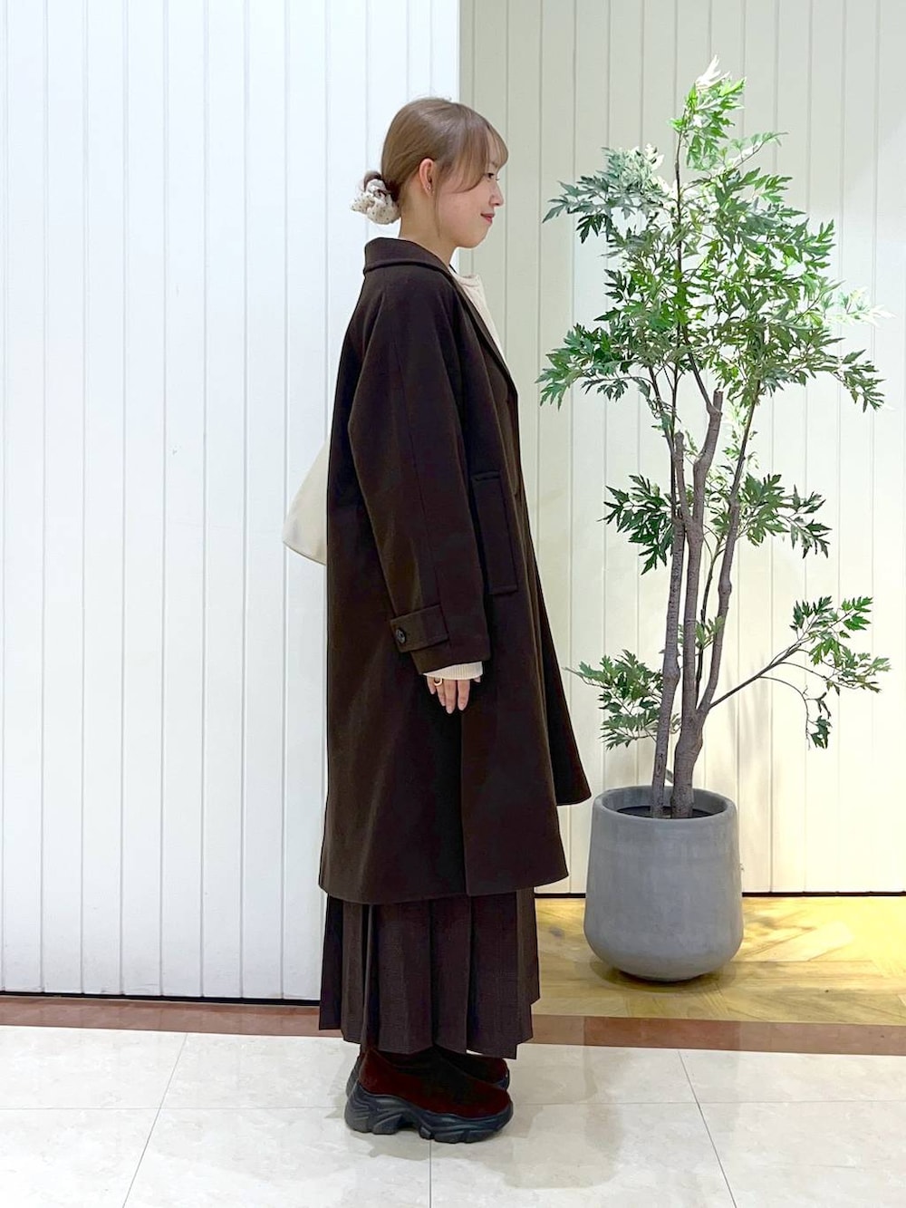 ブラウン系のショルダーバッグ、ブラウン系のブーツ、ブラウン系のスカートを着用したレディースの秋コーディネートの2枚目の写真