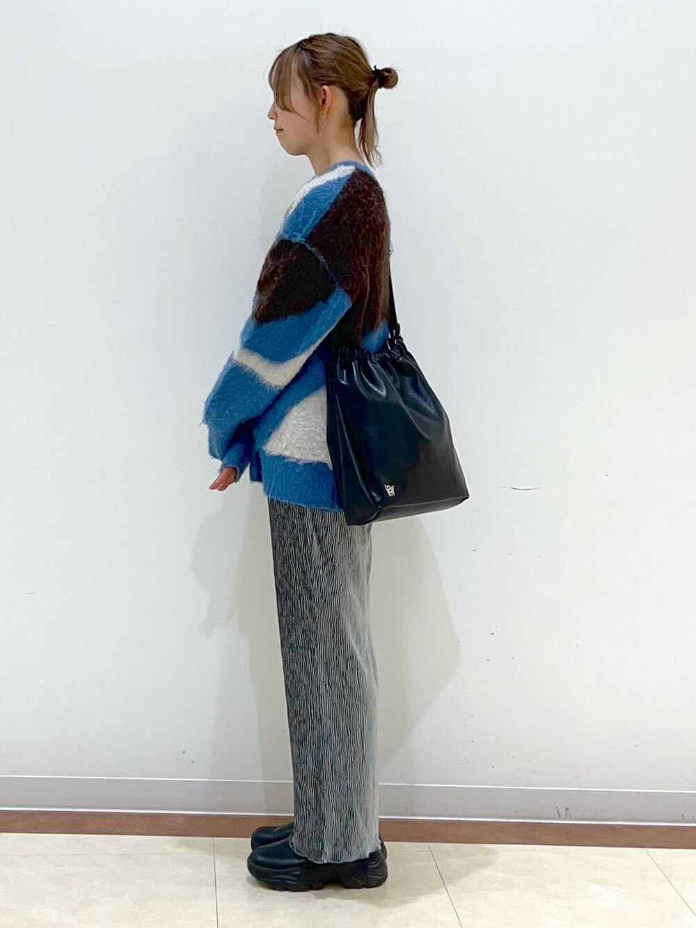 ブラック系のブーツ、グレー系のその他パンツ、ブルー系のニット/セーターを着用したレディースの冬コーディネートの2枚目の写真