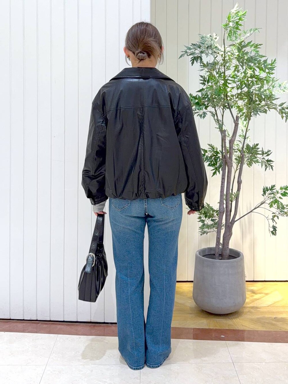 グレー系のスウェット、ブラック系のブルゾン、ブルー系のデニムパンツを着用したレディースの冬コーディネートの3枚目の写真