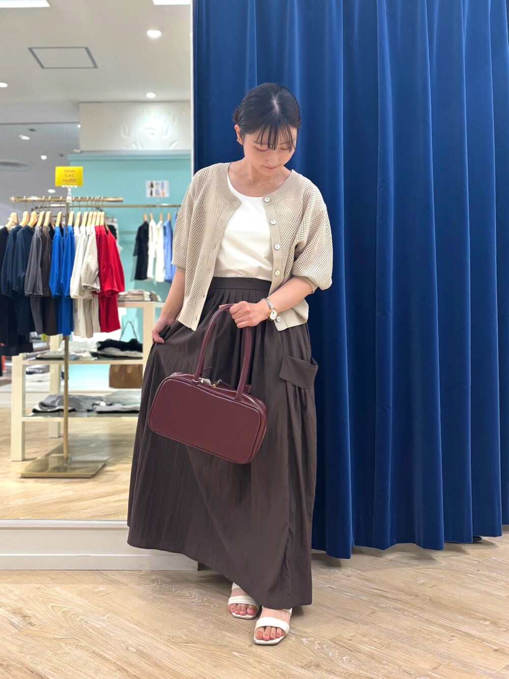 ブラウン系のスカート、レッド系のボストンバッグ、ベージュ系のカーディガン/ボレロを着用したレディースの夏コーディネートの6枚目の写真