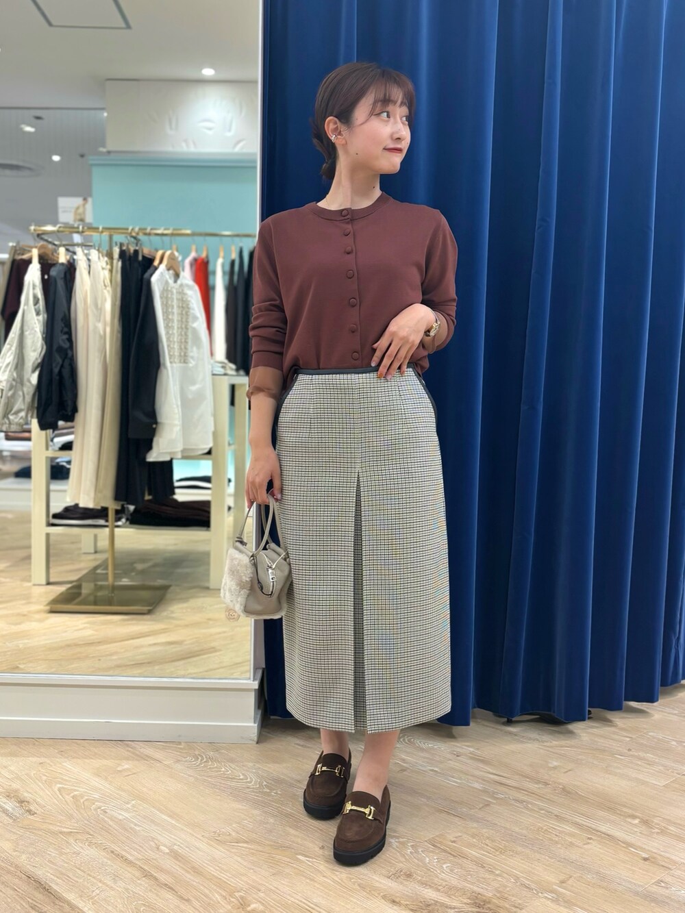 ブラック系のスカート、ベージュ系のショルダーバッグ、ブラウン系のカーディガン/ボレロを着用したレディースの秋コーディネートの6枚目の写真