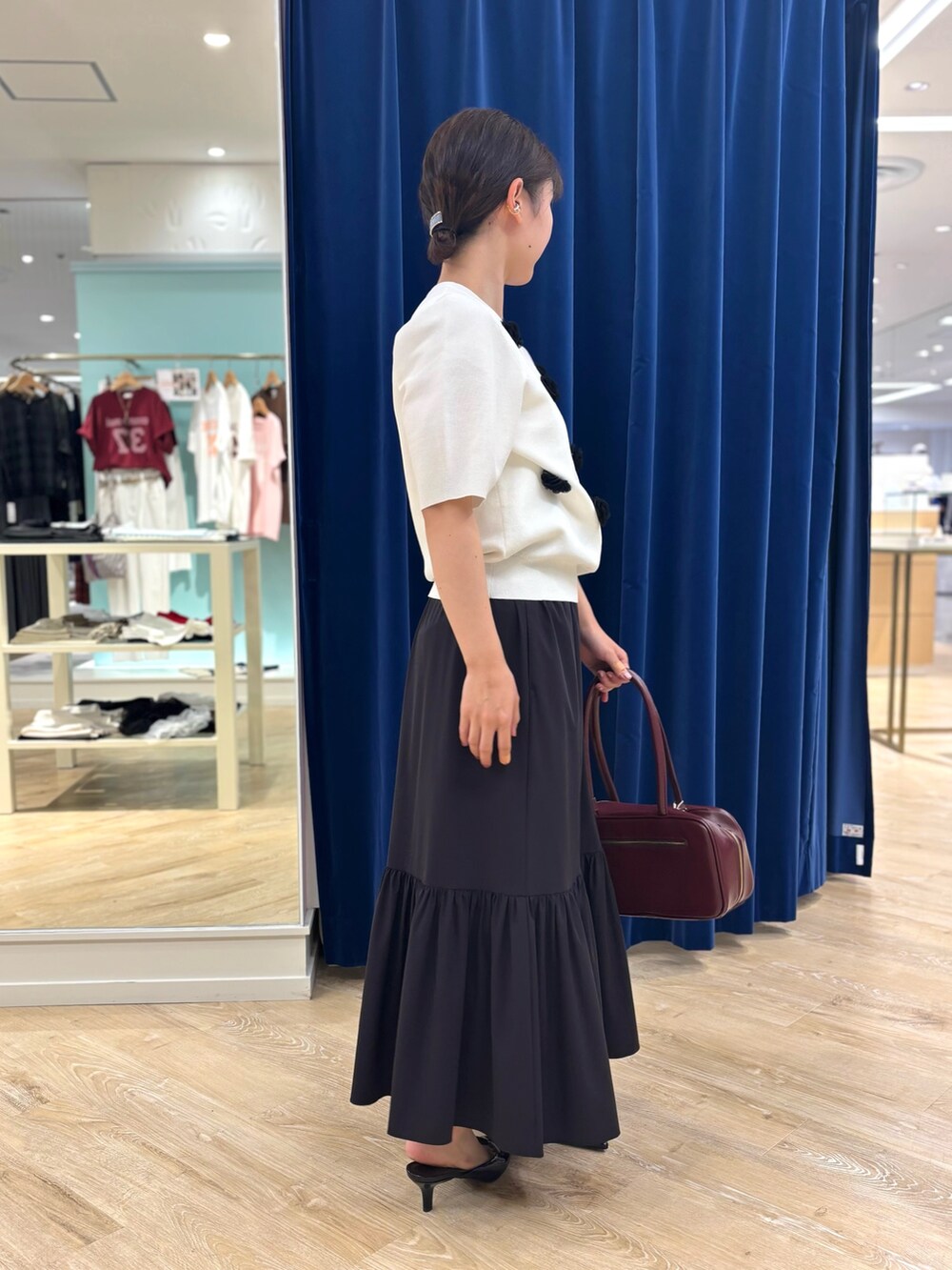 ホワイト系のニット/セーター、ブラック系のスカート、レッド系のボストンバッグを着用したレディースの夏コーディネートの7枚目の写真