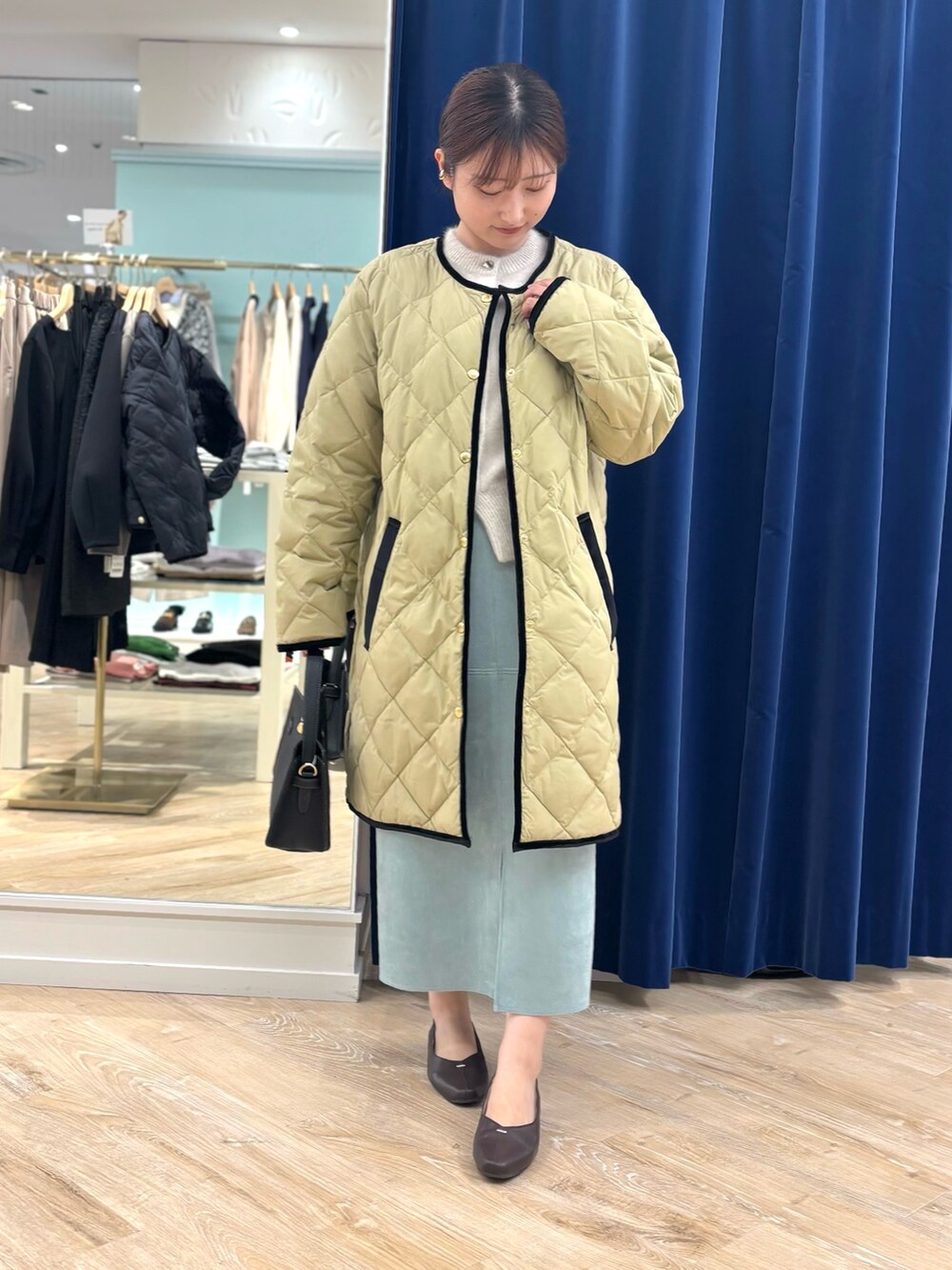 ベージュ系のダウンジャケット/コート、ブラック系のショルダーバッグ、グリーン系のスカートを着用したレディースの秋コーディネートの2枚目の写真