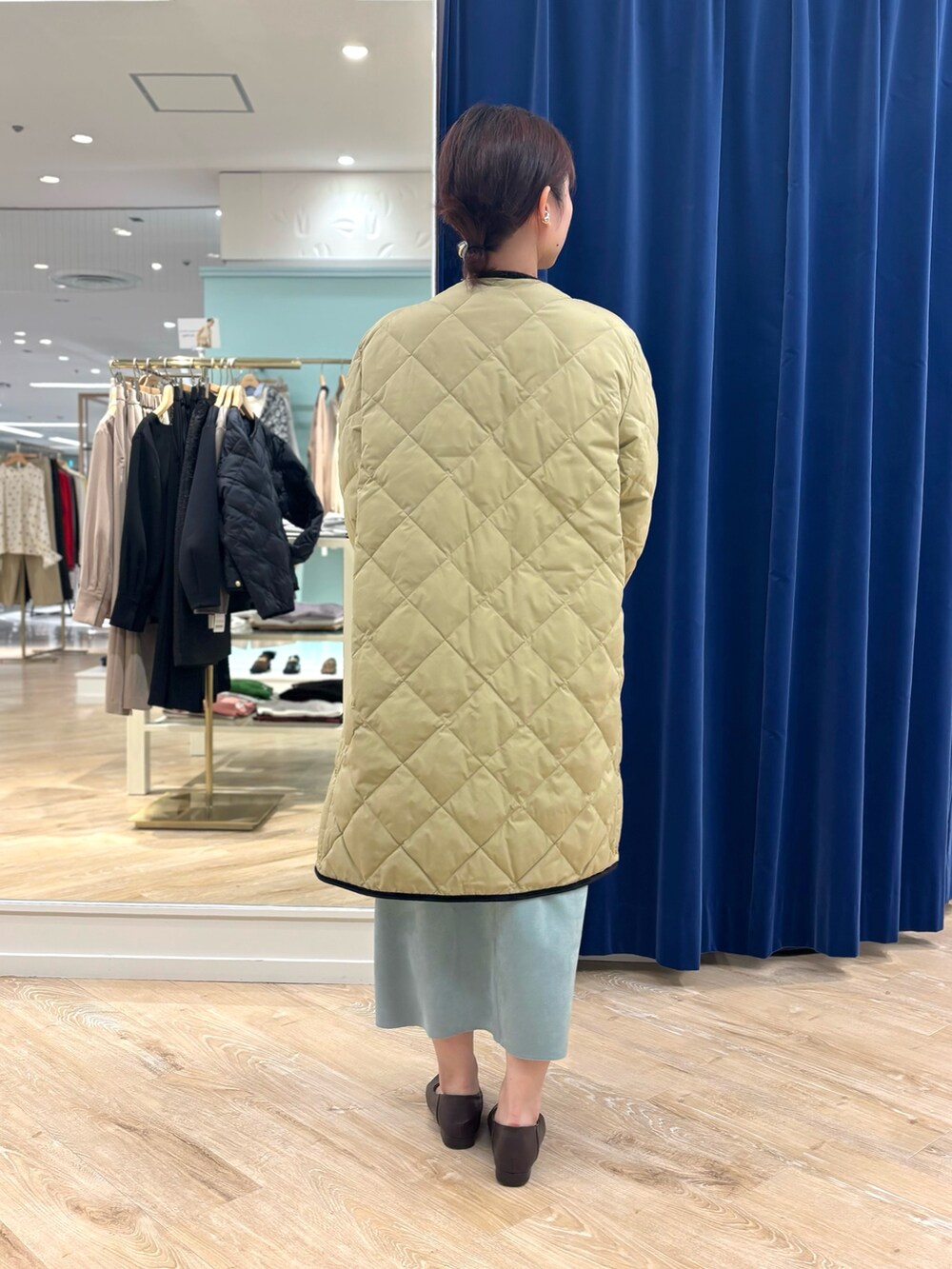 ベージュ系のダウンジャケット/コート、ブラック系のショルダーバッグ、グリーン系のスカートを着用したレディースの秋コーディネートの4枚目の写真