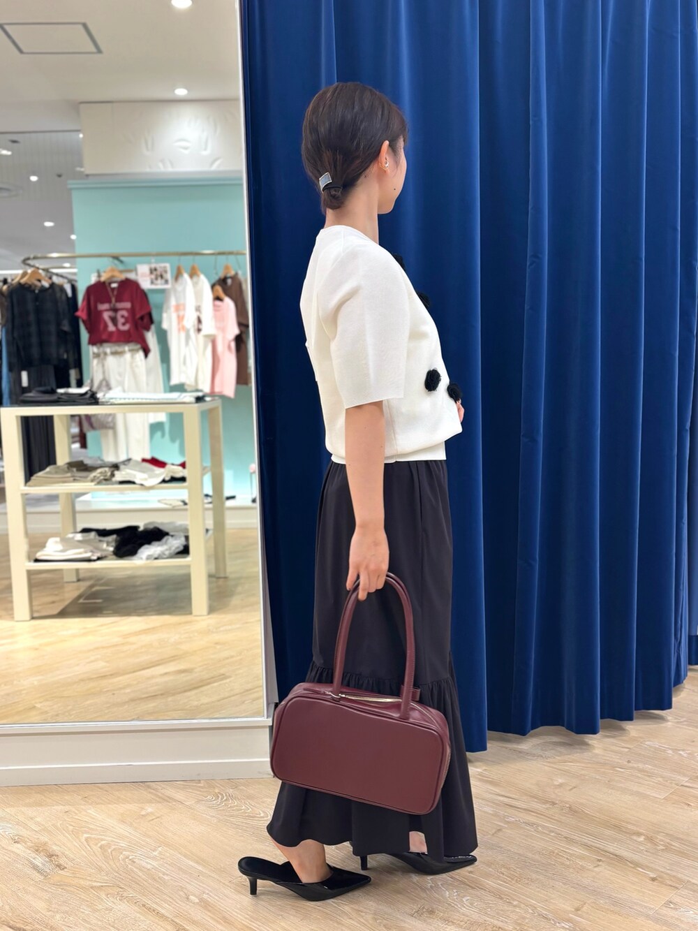 ホワイト系のニット/セーター、ブラック系のスカート、レッド系のボストンバッグを着用したレディースの夏コーディネートの3枚目の写真