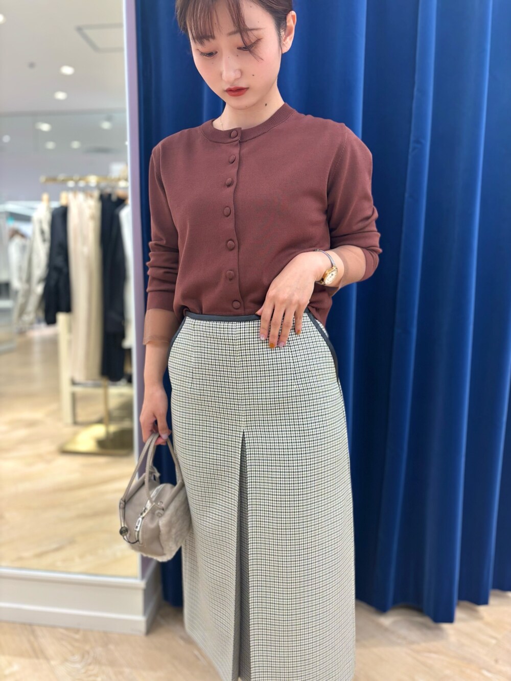 ブラック系のスカート、ベージュ系のショルダーバッグ、ブラウン系のカーディガン/ボレロを着用したレディースの秋コーディネートの9枚目の写真