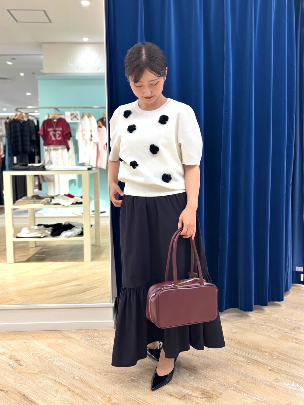 ホワイト系のニット/セーター、ブラック系のスカート、レッド系のボストンバッグを着用したレディースの夏コーディネートの5枚目の写真