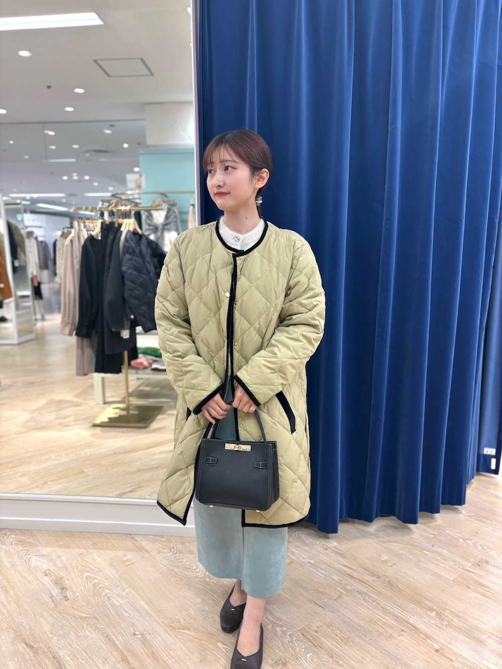 ベージュ系のダウンジャケット/コート、ブラック系のショルダーバッグ、グリーン系のスカートを着用したレディースの秋コーディネートの8枚目の写真