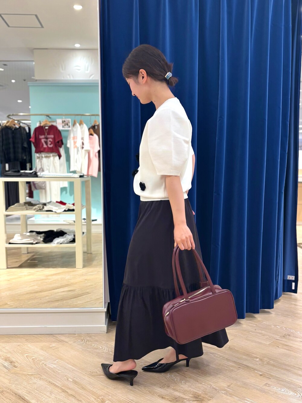 ホワイト系のニット/セーター、ブラック系のスカート、レッド系のボストンバッグを着用したレディースの夏コーディネートの6枚目の写真