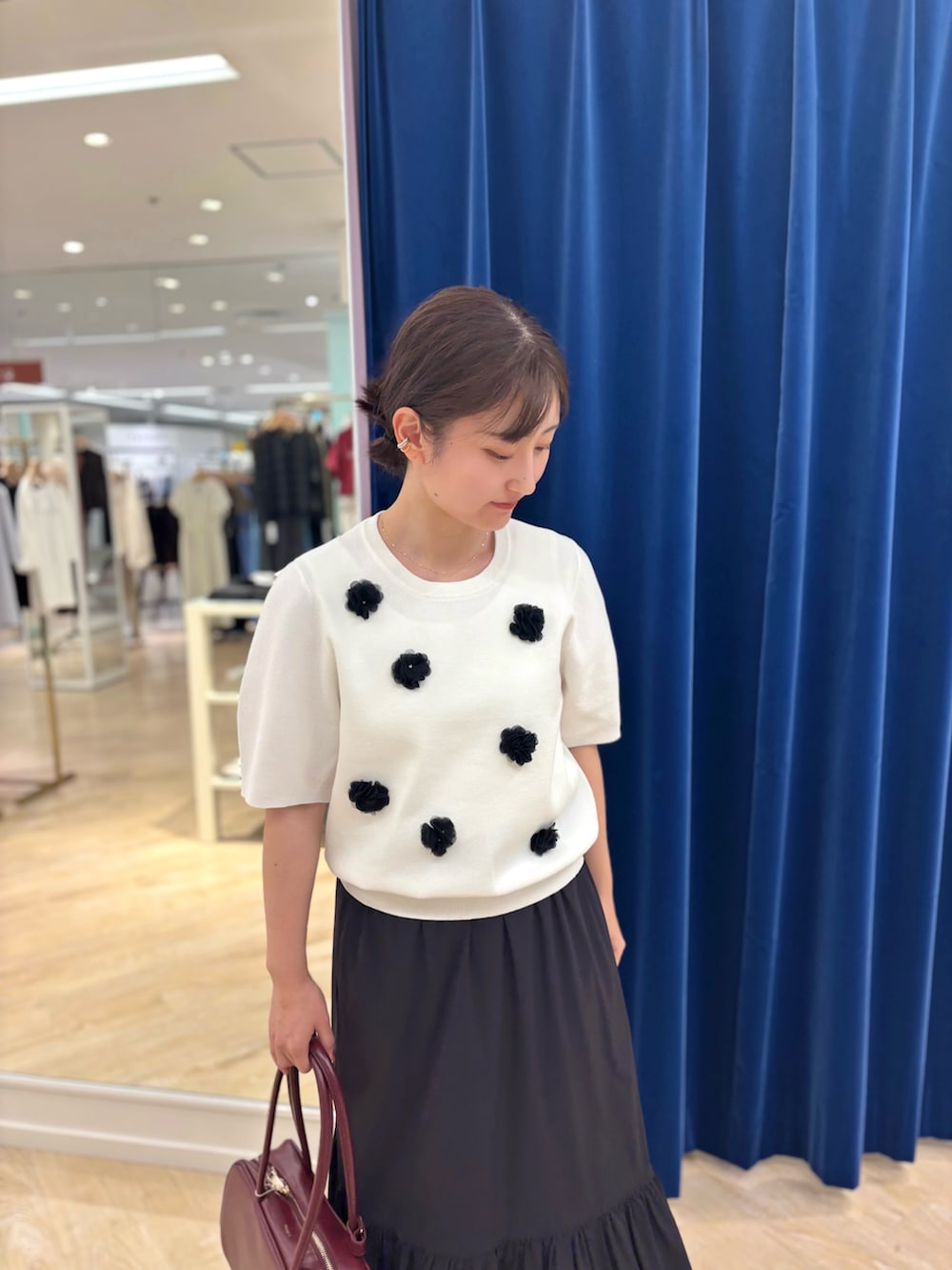 ホワイト系のニット/セーター、ブラック系のスカート、レッド系のボストンバッグを着用したレディースの夏コーディネートの8枚目の写真