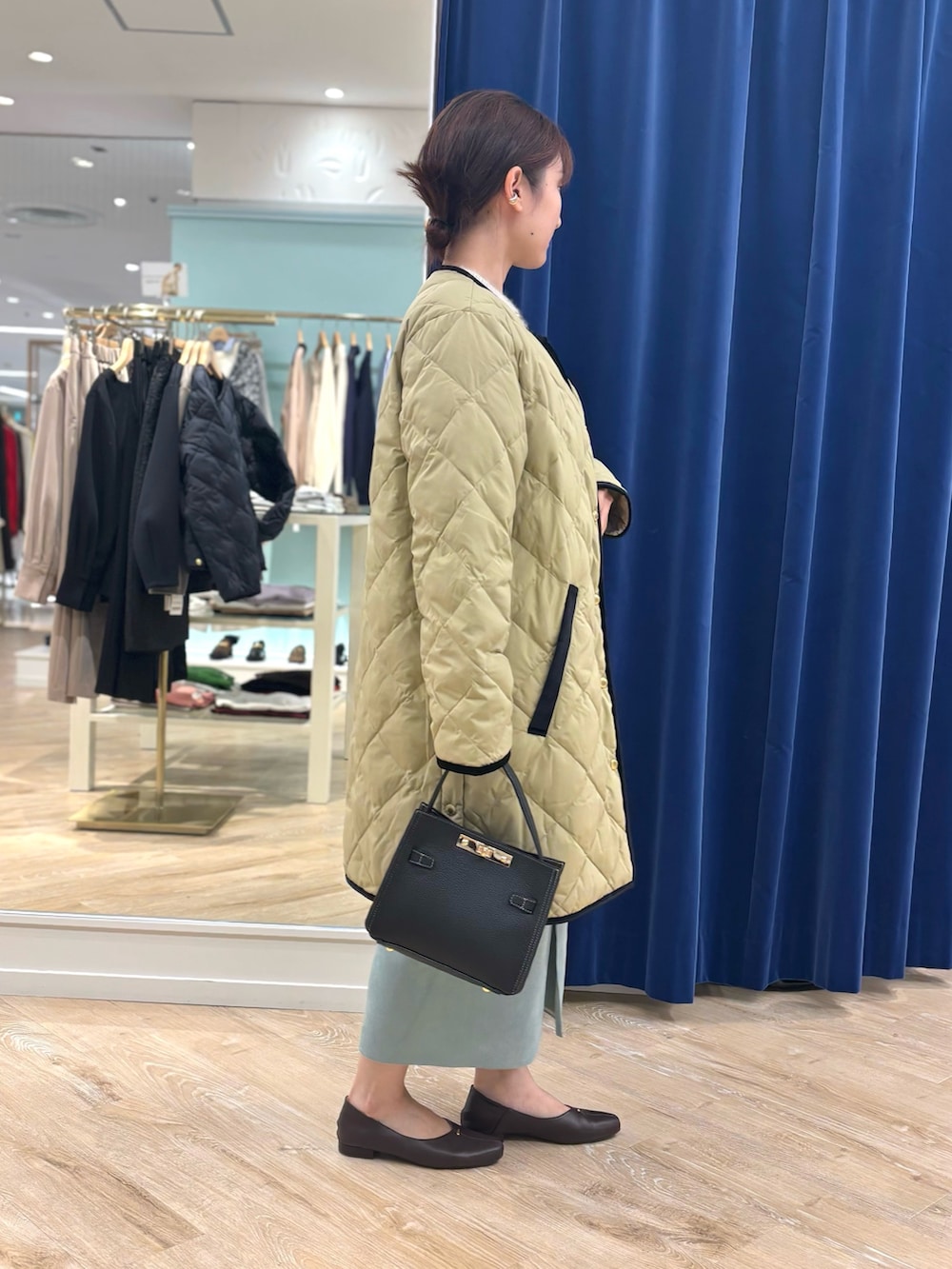 ベージュ系のダウンジャケット/コート、ブラック系のショルダーバッグ、グリーン系のスカートを着用したレディースの秋コーディネートの6枚目の写真