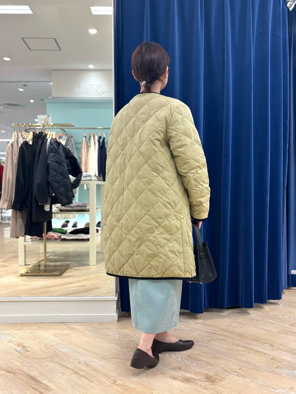 ベージュ系のダウンジャケット/コート、ブラック系のショルダーバッグ、グリーン系のスカートを着用したレディースの秋コーディネートの5枚目の写真