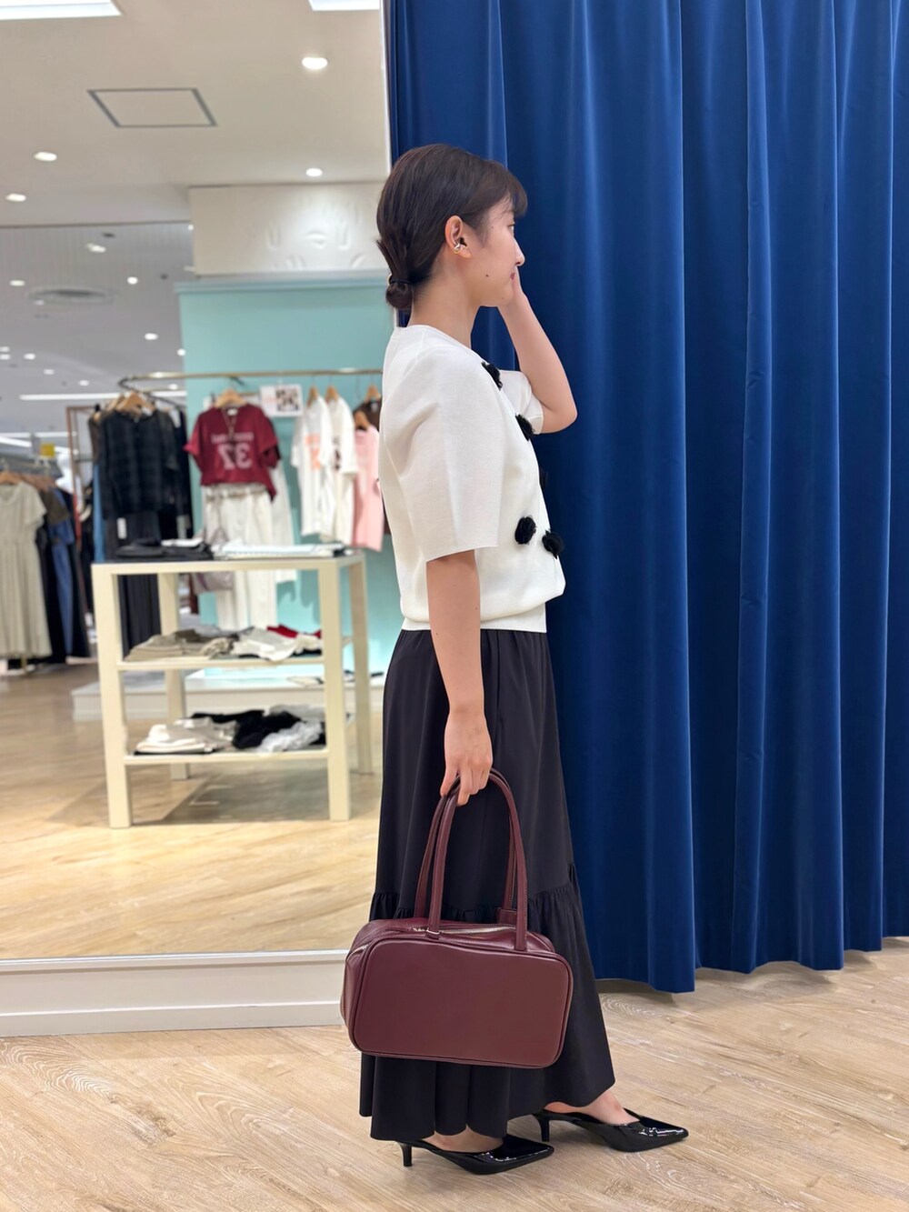 ホワイト系のニット/セーター、ブラック系のスカート、レッド系のボストンバッグを着用したレディースの夏コーディネートの2枚目の写真