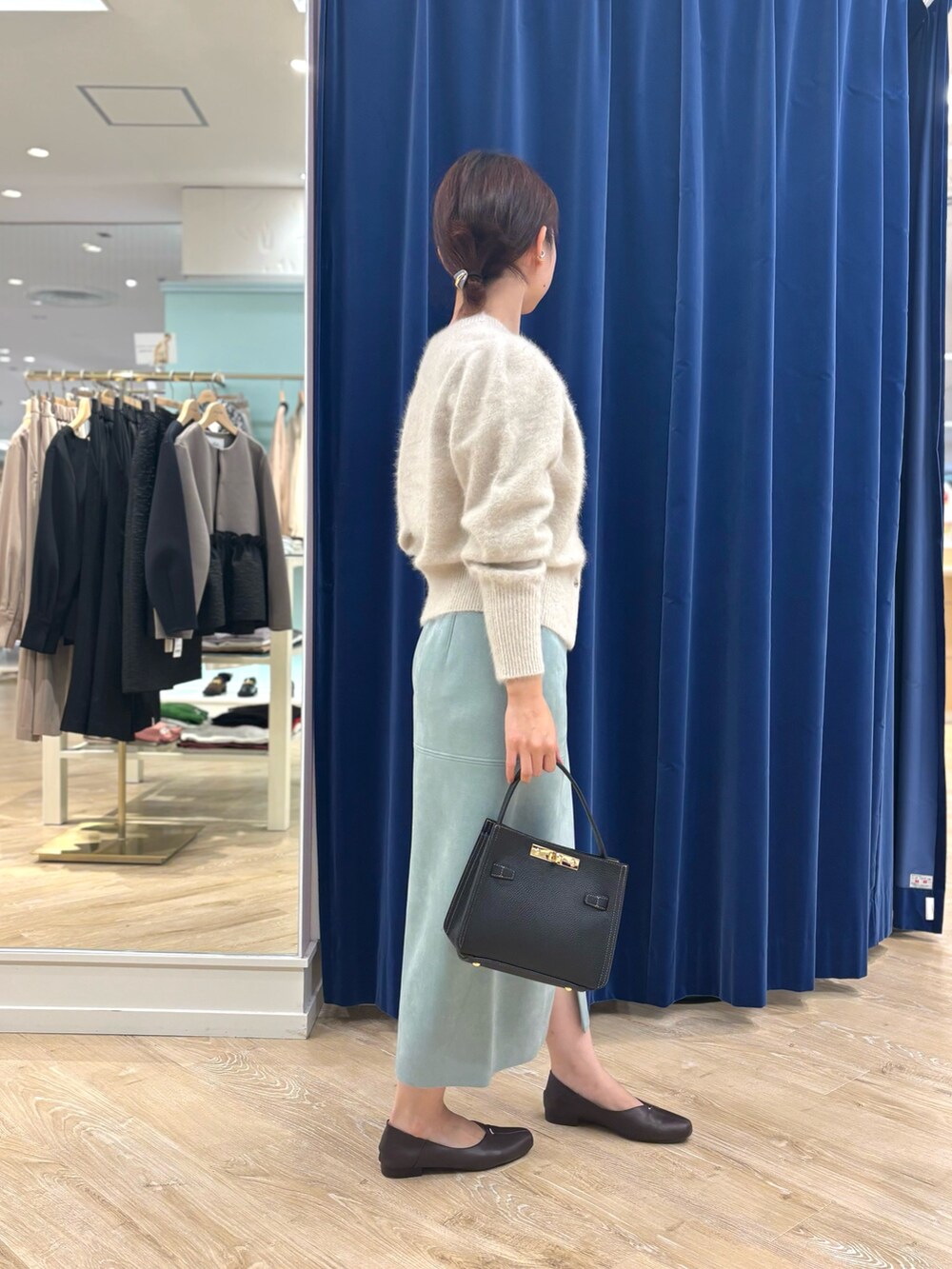 ベージュ系のカーディガン/ボレロ、ブラック系のショルダーバッグ、グリーン系のスカートを着用したレディースの秋コーディネートの3枚目の写真