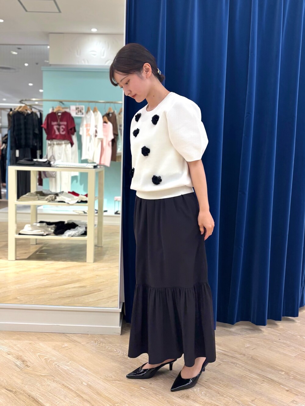 ホワイト系のニット/セーター、ブラック系のスカート、レッド系のボストンバッグを着用したレディースの夏コーディネートの4枚目の写真