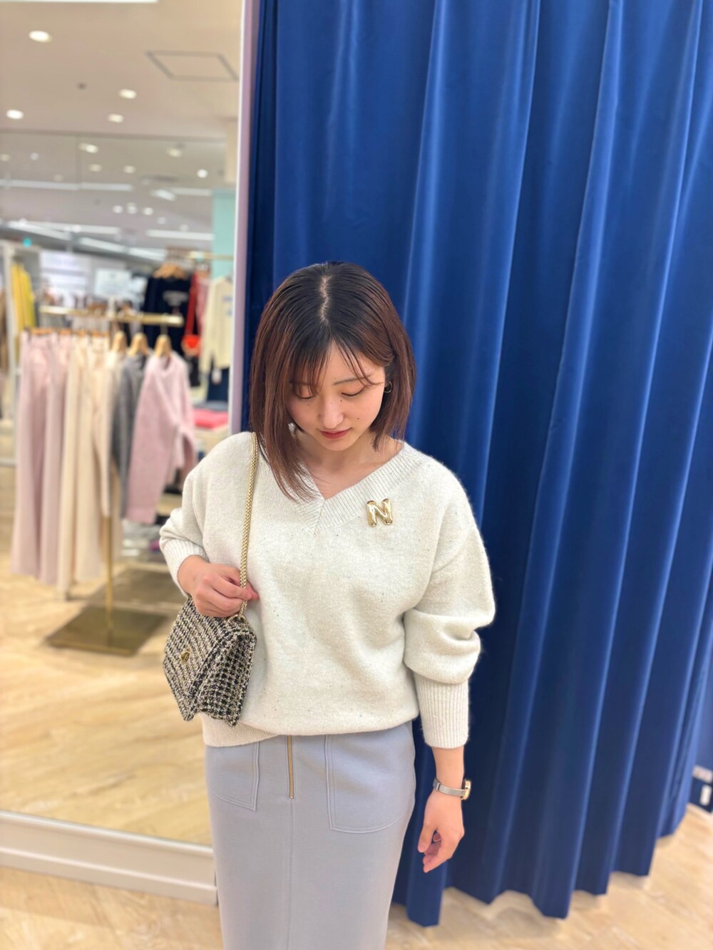 ゴールド系のショルダーバッグ、ブルー系のスカート、ホワイト系のニット/セーターを着用したレディースの冬コーディネートの7枚目の写真