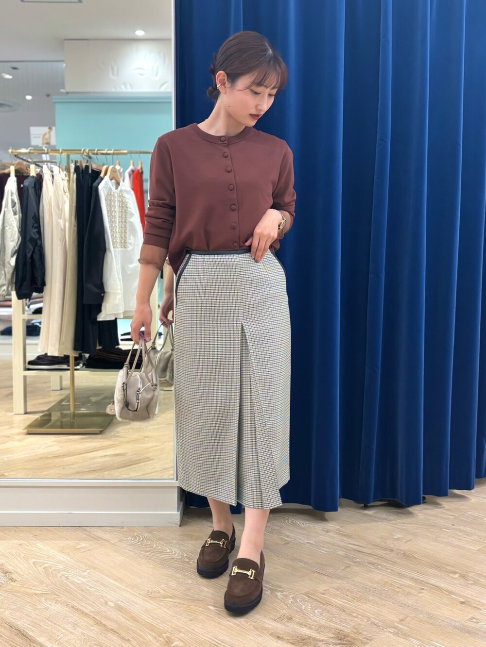 ブラック系のスカート、ベージュ系のショルダーバッグ、ブラウン系のカーディガン/ボレロを着用したレディースの秋コーディネートの2枚目の写真