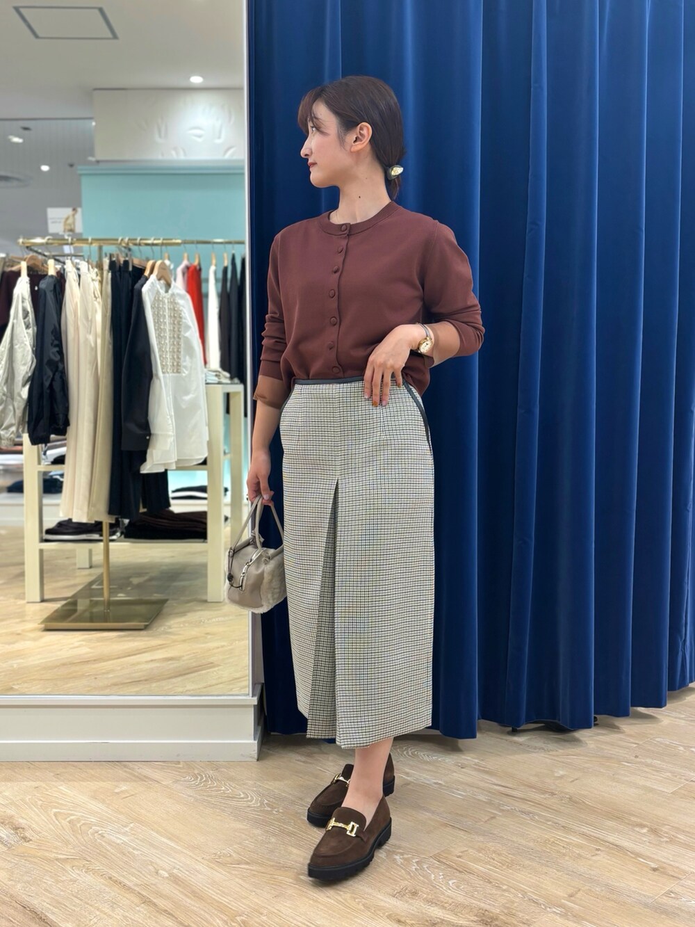 ブラック系のスカート、ベージュ系のショルダーバッグ、ブラウン系のカーディガン/ボレロを着用したレディースの秋コーディネートの7枚目の写真