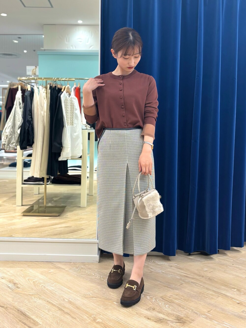 ブラック系のスカート、ベージュ系のショルダーバッグ、ブラウン系のカーディガン/ボレロを着用したレディースの秋コーディネートの3枚目の写真