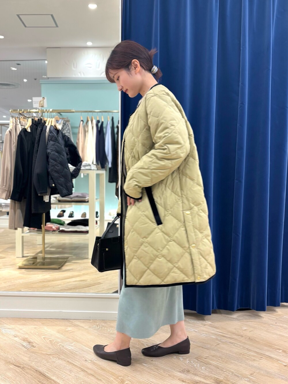 ベージュ系のダウンジャケット/コート、ブラック系のショルダーバッグ、グリーン系のスカートを着用したレディースの秋コーディネートの3枚目の写真