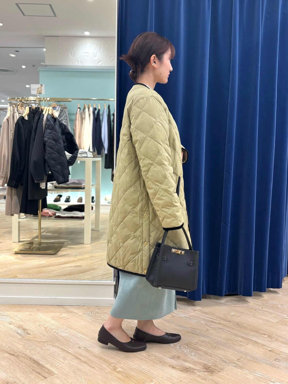 ベージュ系のダウンジャケット/コート、ブラック系のショルダーバッグ、グリーン系のスカートを着用したレディースの秋コーディネートの7枚目の写真