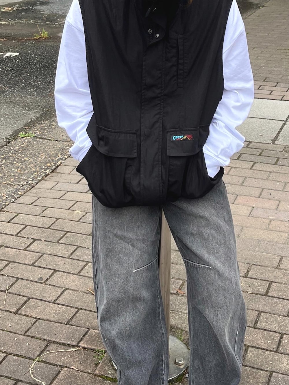 ブラック系のベスト、ホワイト系のスニーカー、ブラック系のキャップを着用したレディースの夏コーディネートの2枚目の写真