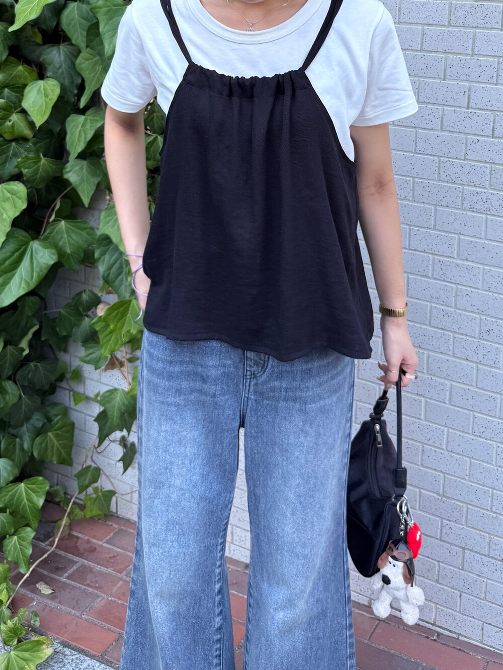 ブラック系のキャミソール、ホワイト系のTシャツ/カットソー、ブルー系のデニムパンツを着用したレディースの夏コーディネートの3枚目の写真