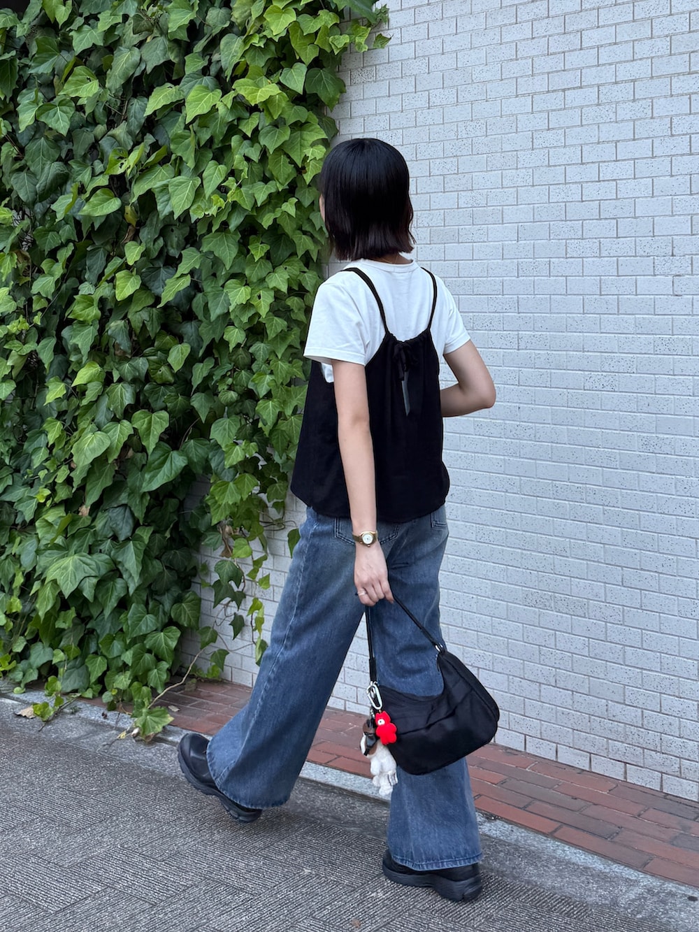 ブラック系のキャミソール、ホワイト系のTシャツ/カットソー、ブルー系のデニムパンツを着用したレディースの夏コーディネートの2枚目の写真