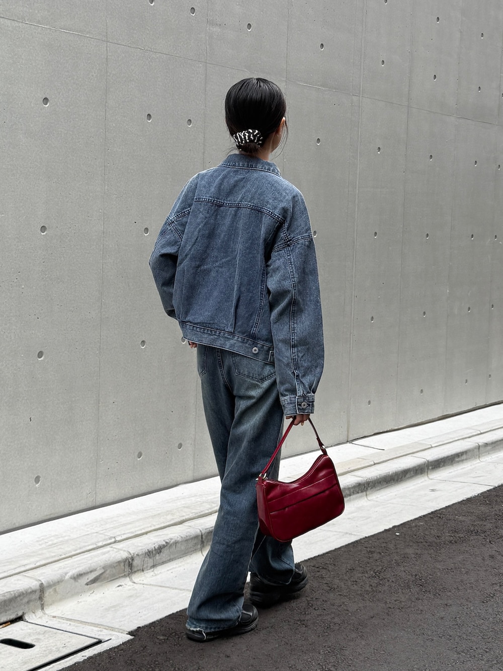 ブルー系のデニムジャケット、ブルー系のデニムパンツ、レッド系のハンドバッグを着用したレディースの秋コーディネートの2枚目の写真