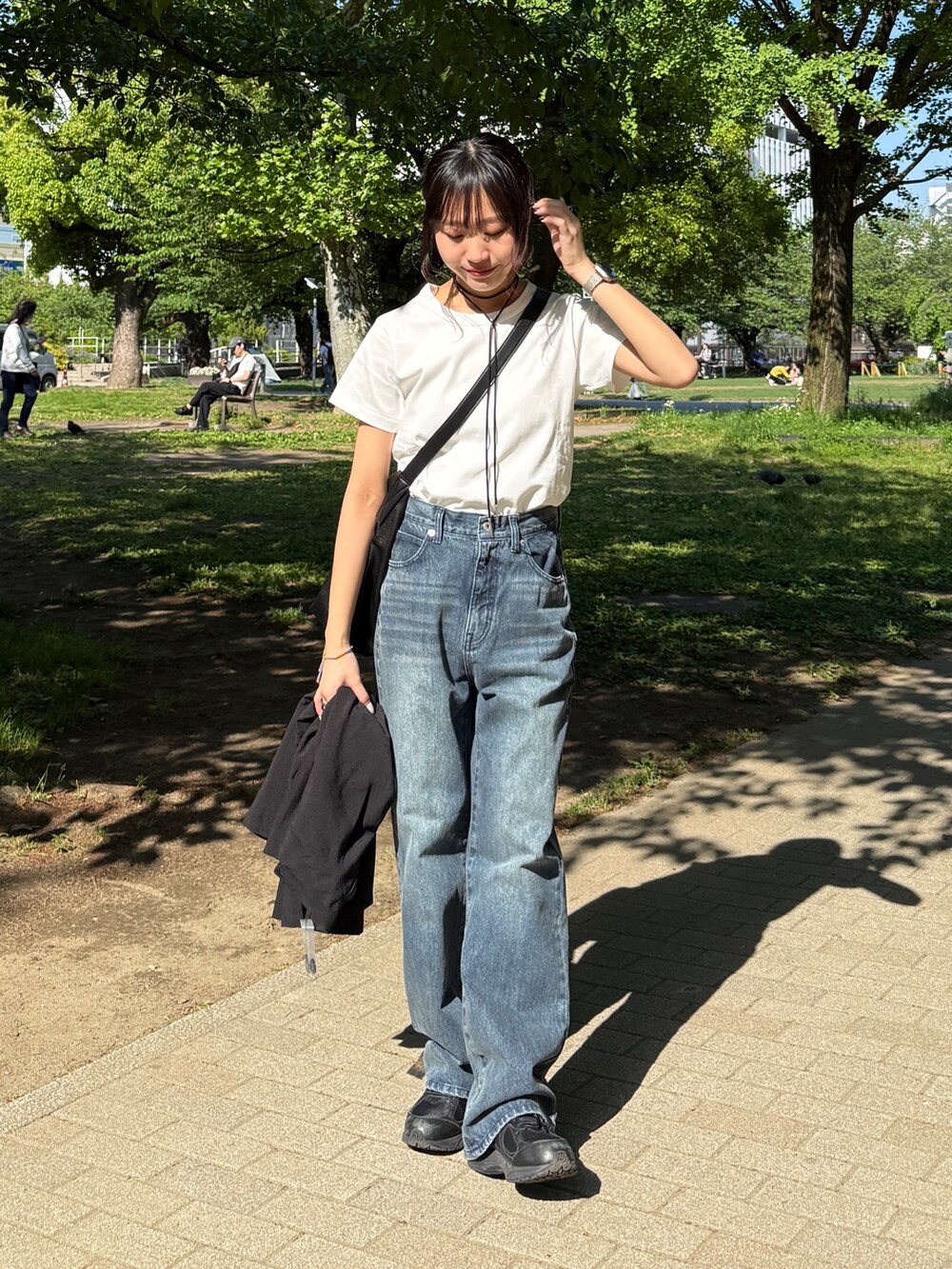ホワイト系のTシャツ/カットソー、ブルー系のデニムパンツ、ブラック系のショルダーバッグを着用したレディースの夏コーディネートの2枚目の写真