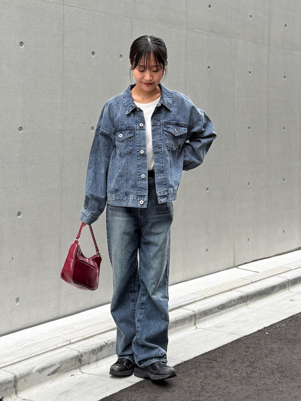 ブルー系のデニムジャケット、ブルー系のデニムパンツ、レッド系のハンドバッグを着用したレディースの秋コーディネートの3枚目の写真