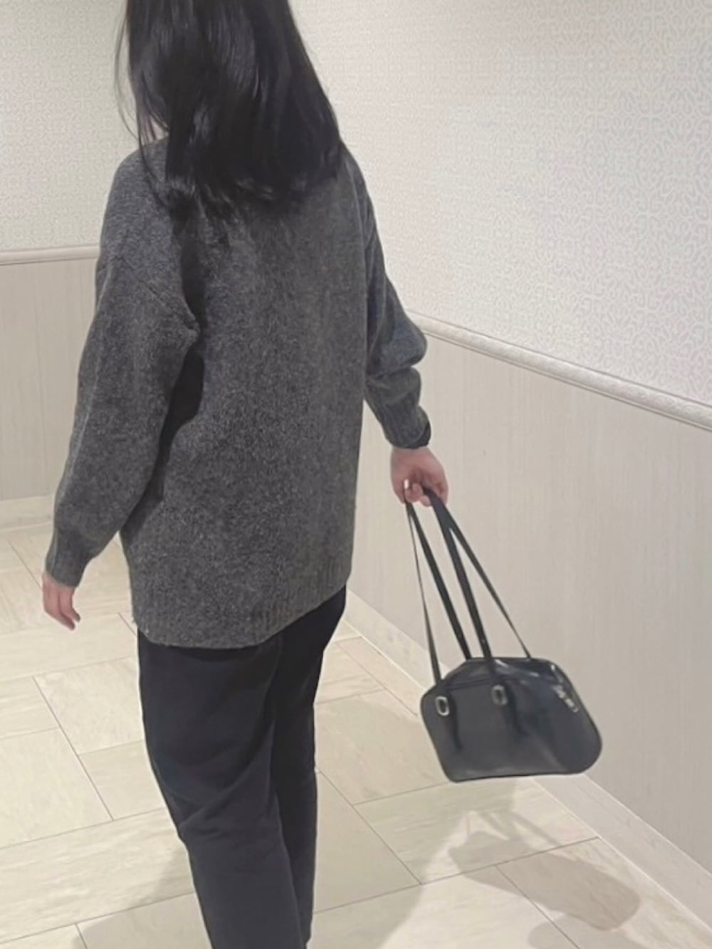 グレー系のニット/セーター、ブラック系のパンツ、ブラック系のスニーカーを着用したレディースの春コーディネートの5枚目の写真