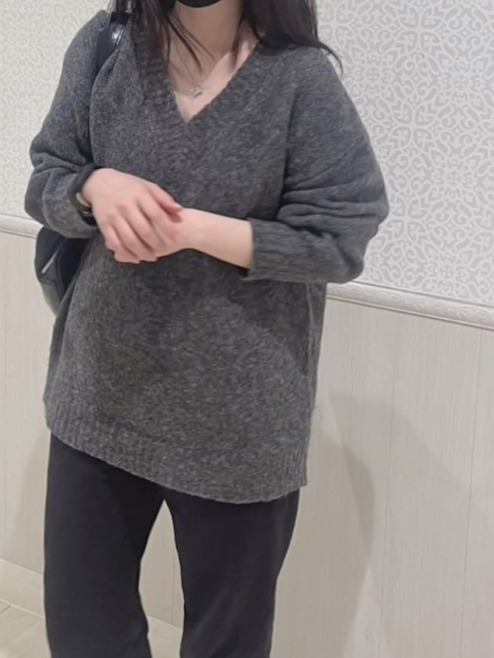 グレー系のニット/セーター、ブラック系のパンツ、ブラック系のスニーカーを着用したレディースの春コーディネートの2枚目の写真