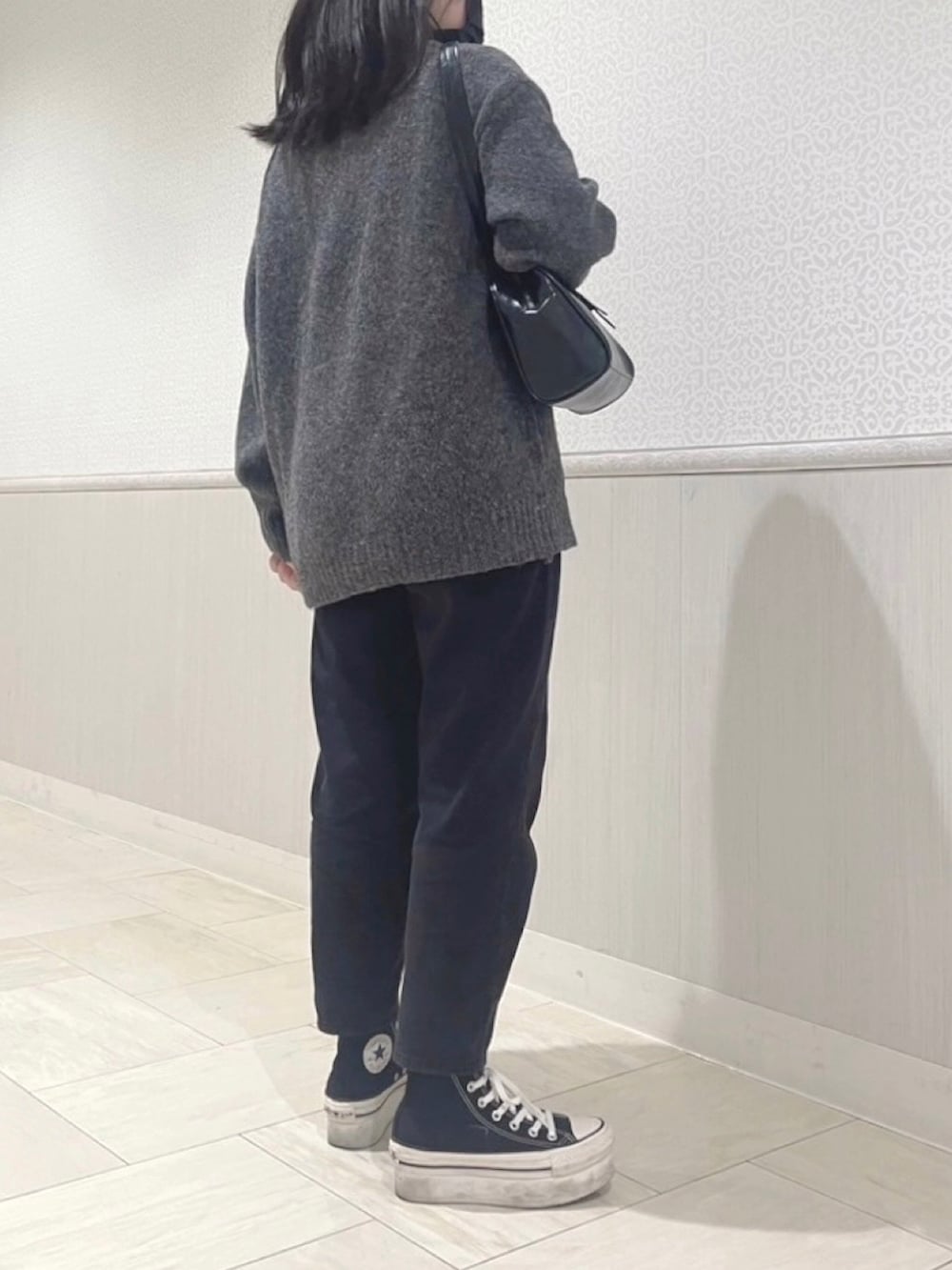 グレー系のニット/セーター、ブラック系のパンツ、ブラック系のスニーカーを着用したレディースの春コーディネートの4枚目の写真