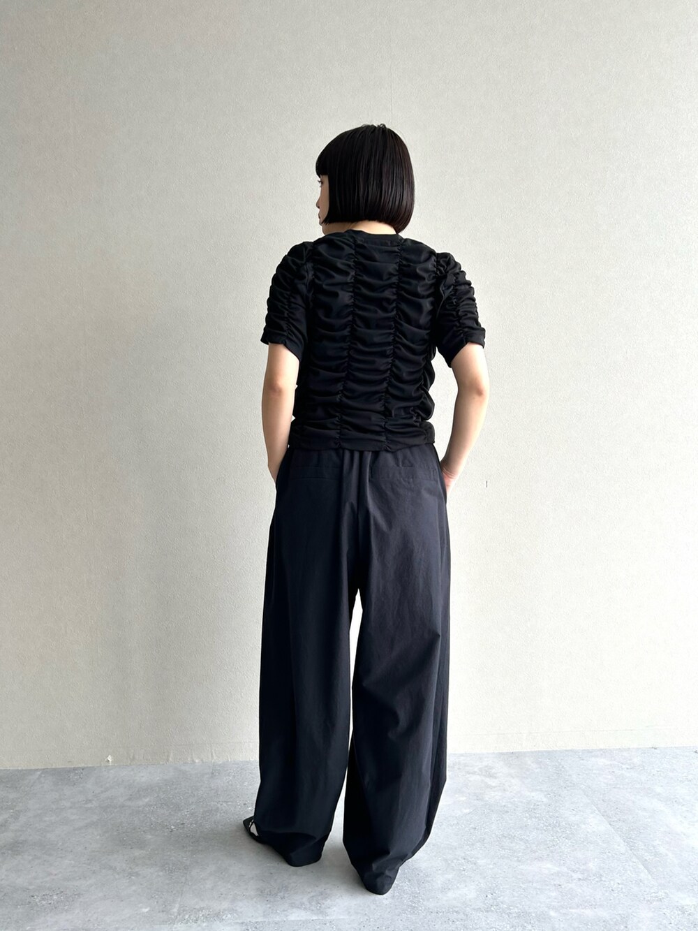 ブラック系のTシャツ/カットソー、ブラック系のパンツ、ブラック系のサンダルを着用したレディースの春コーディネートの2枚目の写真